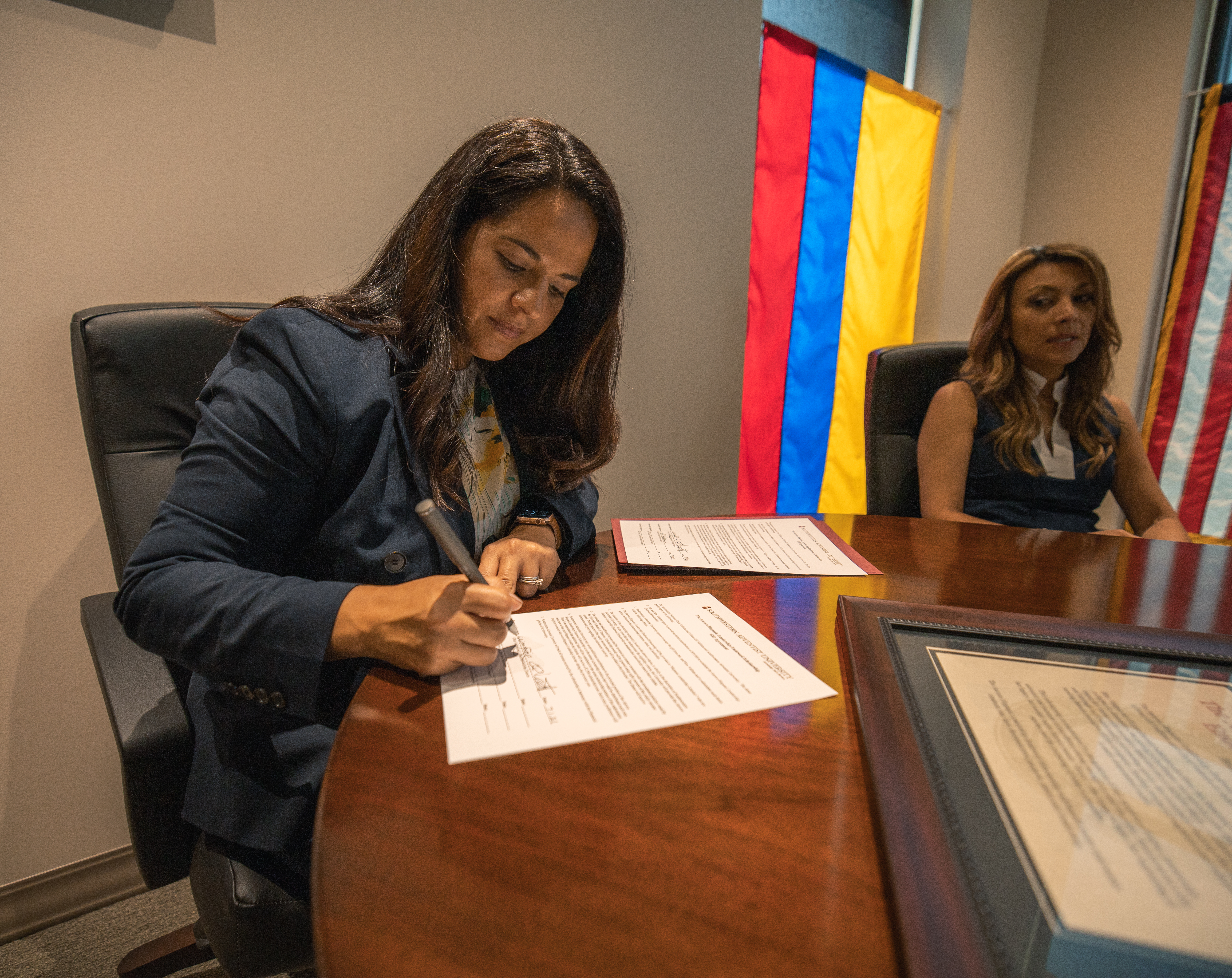Ana Patterson signing an endowment agreement with Liliana Villetta