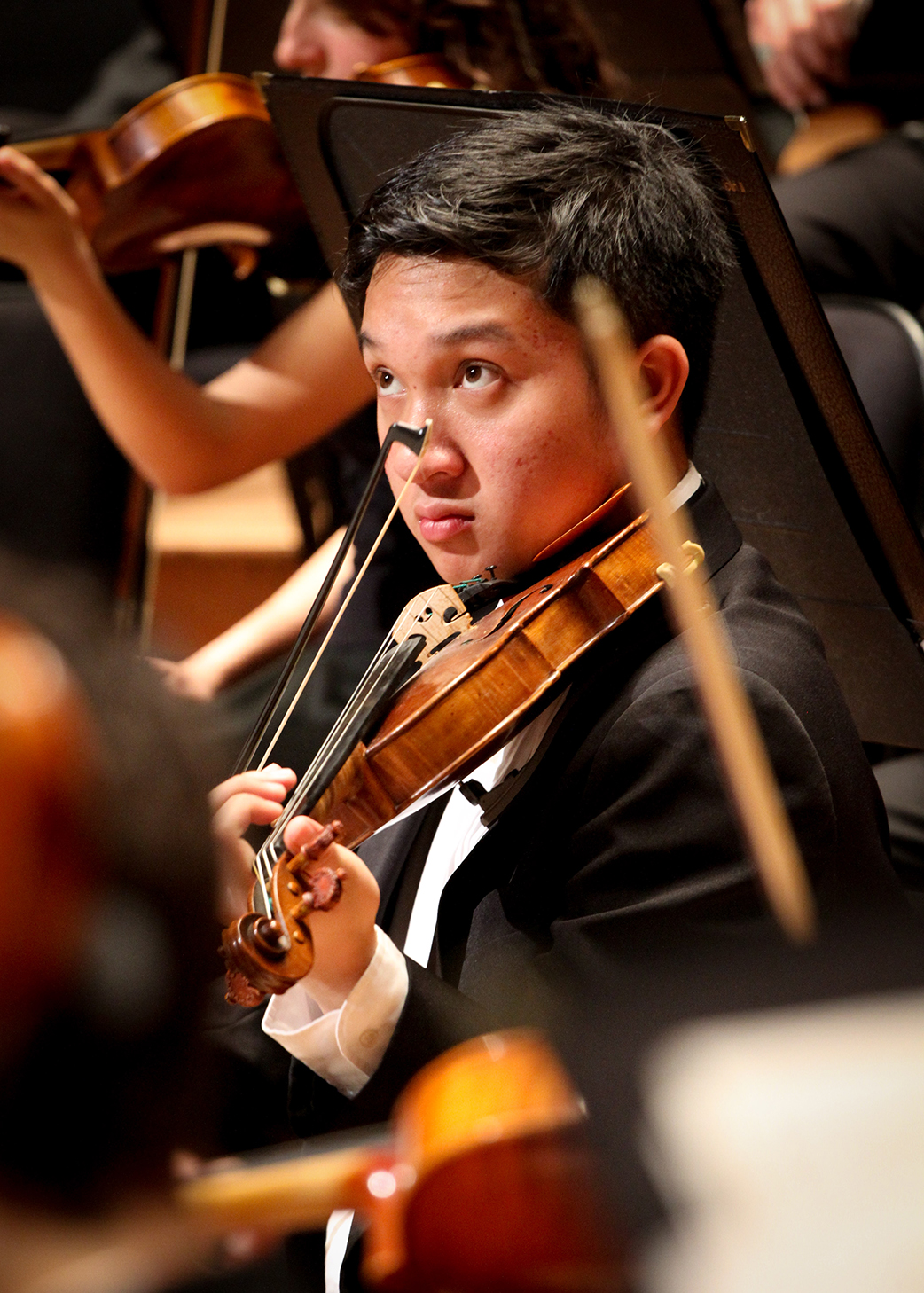 A violinist begins to play while look at the conductor for his cue.