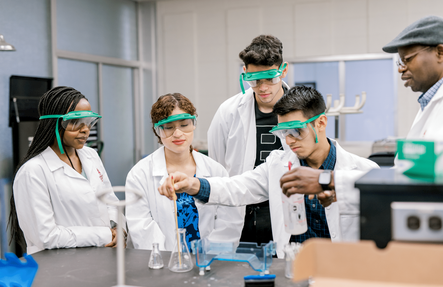 Groups of students with lab coats in lab doing an experiement with the professor