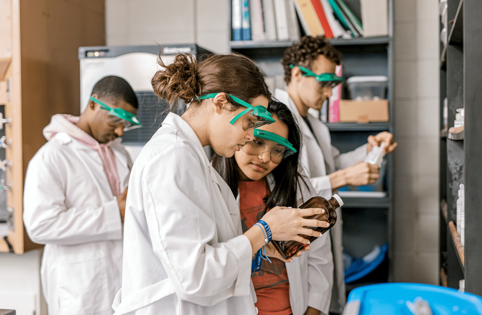 Group of students with lab coats in lab analyzing class materials