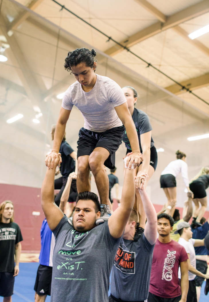 A group of SWAT members practicing lifiting each other on their shoulders at the gym 