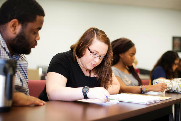 Sitting beside her peers, a student looks down to review her notes