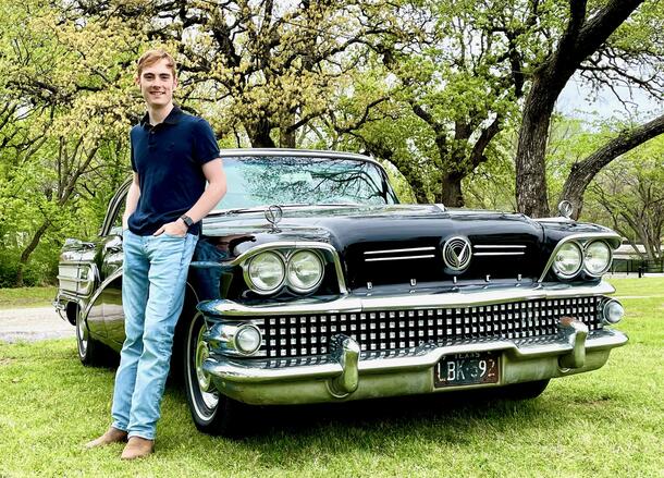 Tony Seery poses leaning against a car in jeans and a polo