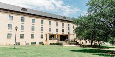 Exterior of Harmon hall which is built with light tan bricks and has various windows for each room