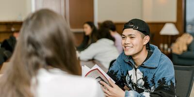 A student smiles as he talks to his peer sitting across from him