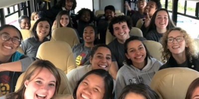 University Singers smile and laugh as they take a picture in their bus