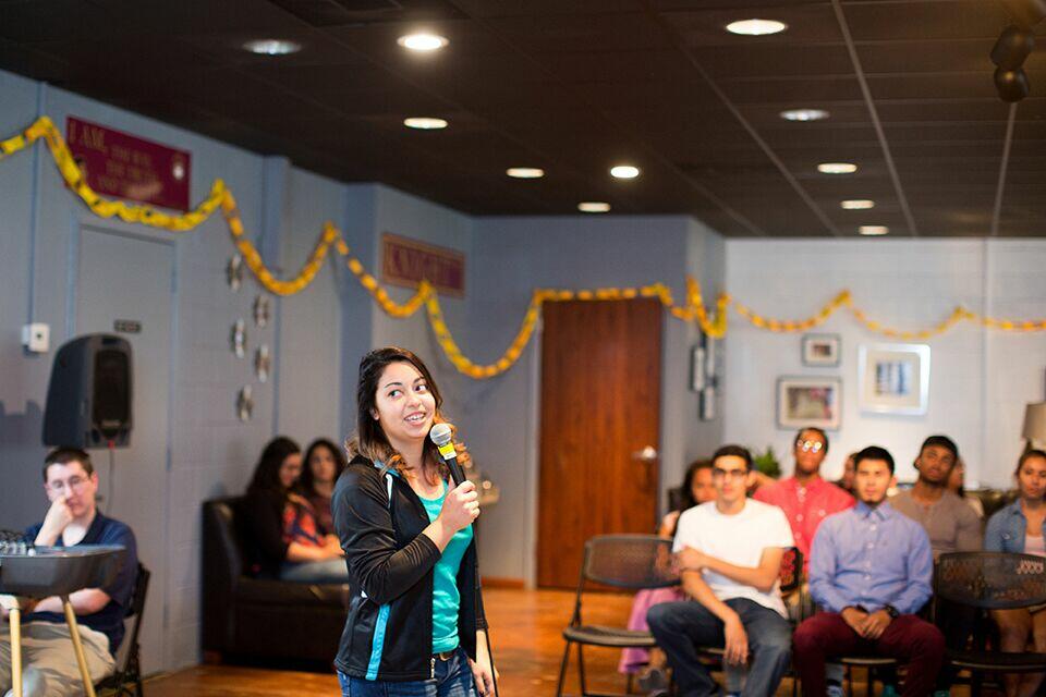 A student stands in front of other students and talks through a microphone.