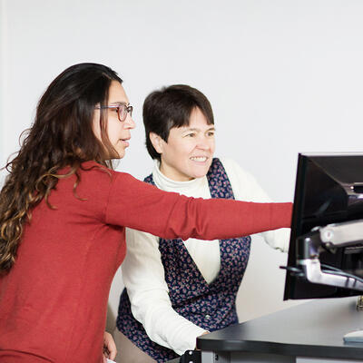 A student points to a computer as she shows the professor something about class