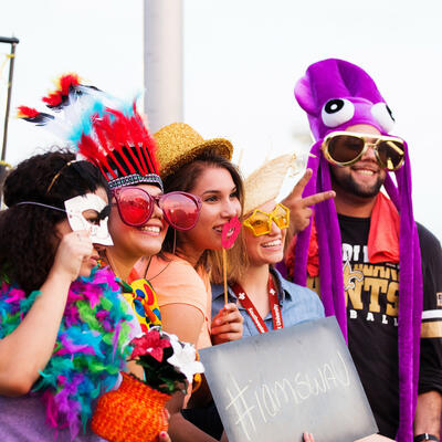 A group of five swau students smile big as they wear silly hats, glasses and other props for a photo