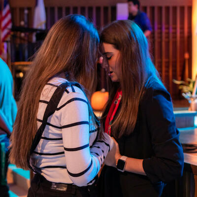 In the Keene Church, two female students hold hands and bow their head as they pray together