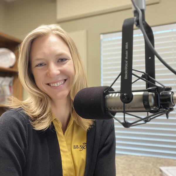 Danae Songy in a yellow 88.3 The Journey shirt in front of a radio mic