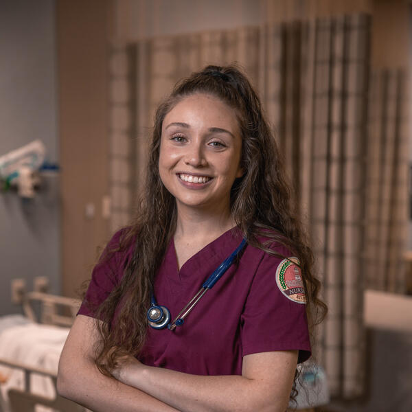 Heather Chirinos poses in the Nursing SIM Lab wearing her SWAU scrubs and a stethoscope