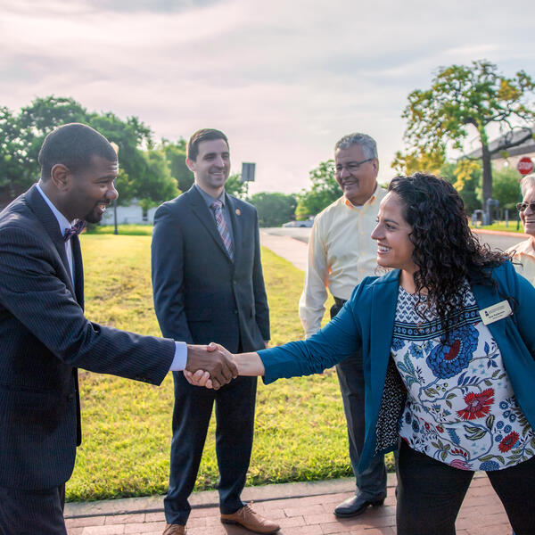 Ana Patterson shakes a man's hand in front of three people