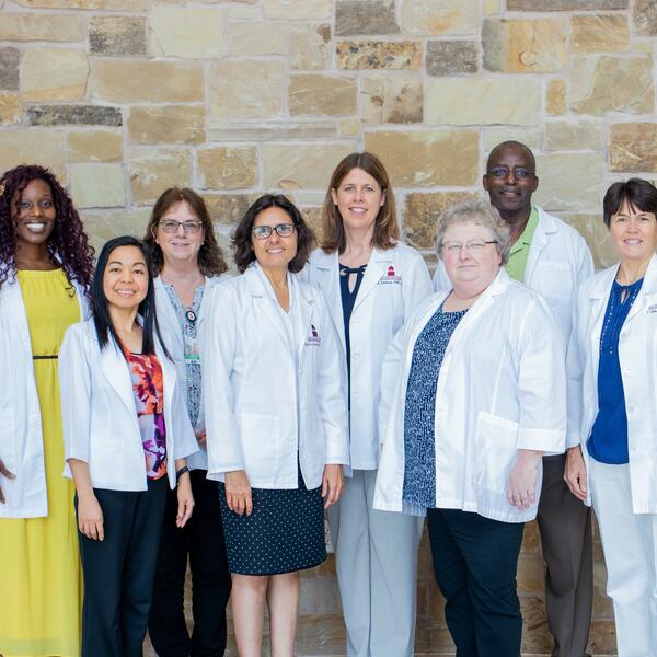 Dressed in their business professional clothes, the nursing administration smiles as they all match in white nursing coats