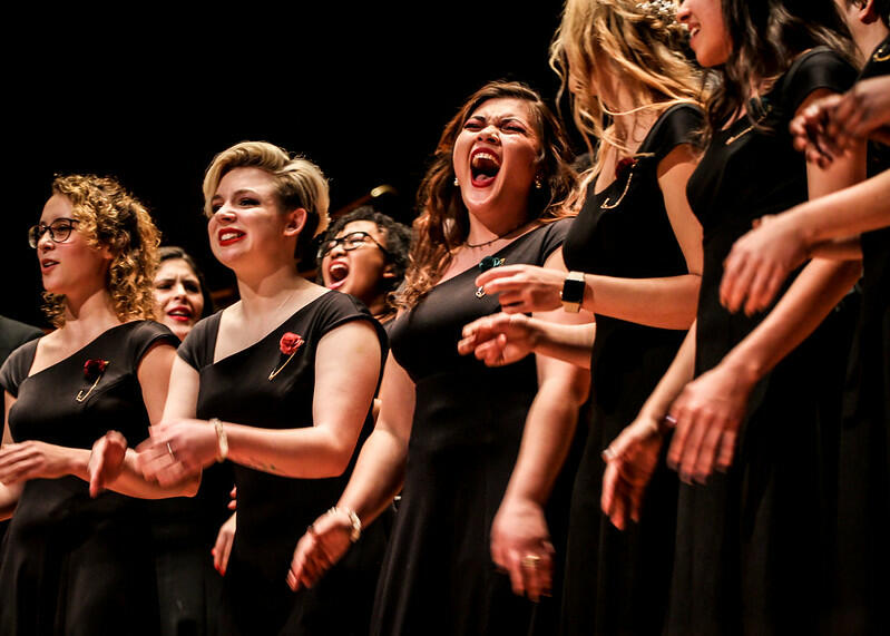 Matching in long black dresses, the women in the choir and laugh and they practice before their event