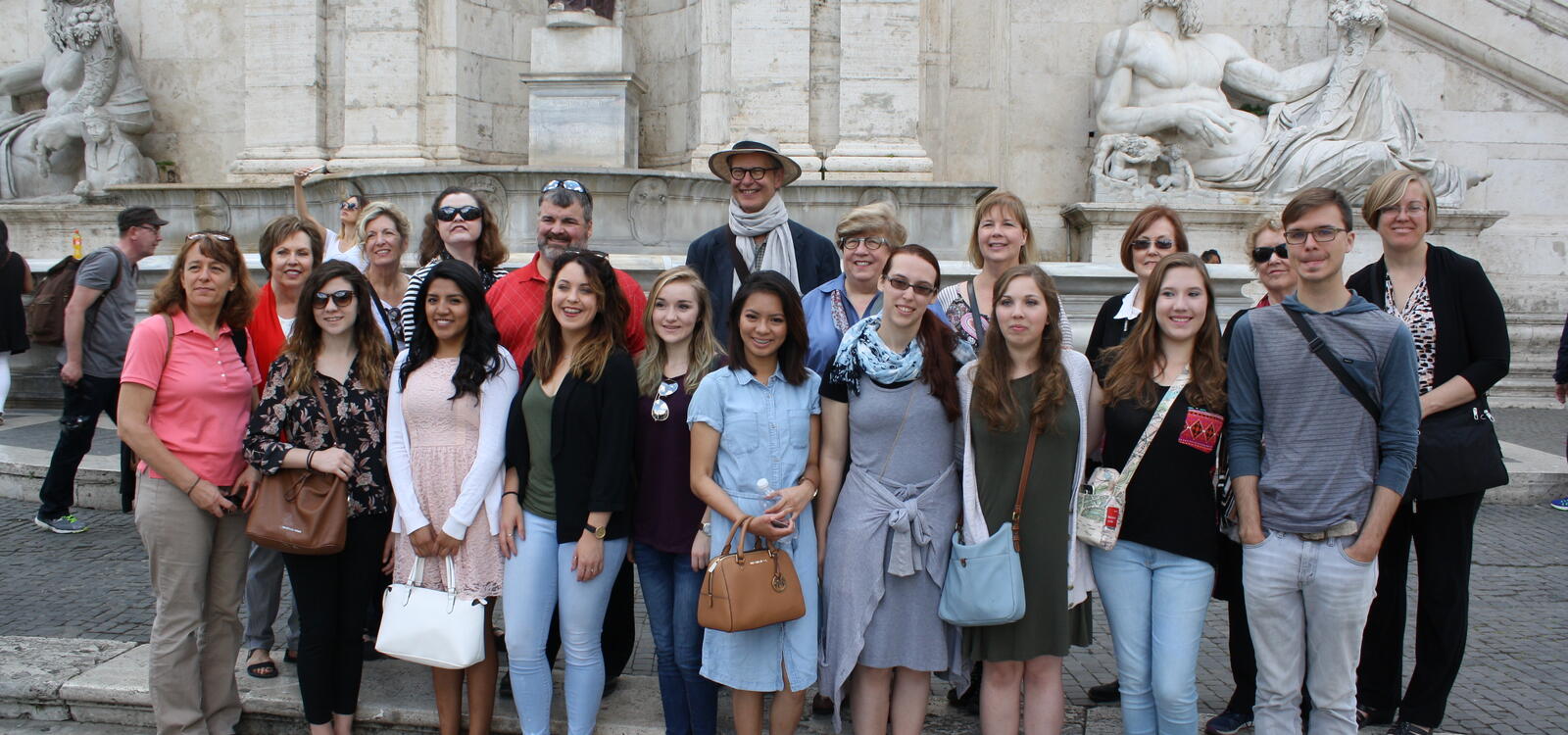 Students from the Honors Program smile as they stand in front of statues of greek mythology