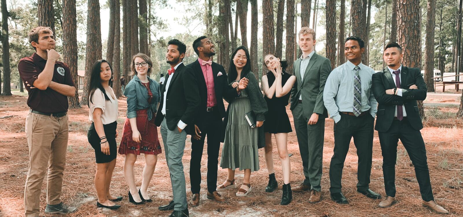 A group of students, all dressed in church clothes, smile and stand in different poses together