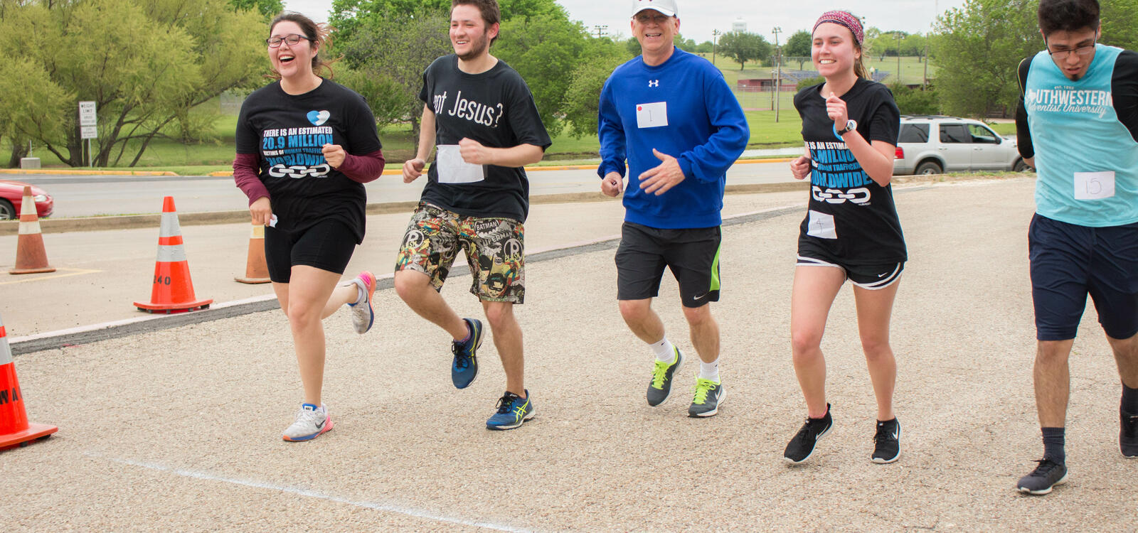 Four students smile and laugh as they run along side the University's President, Dr. Shaw.