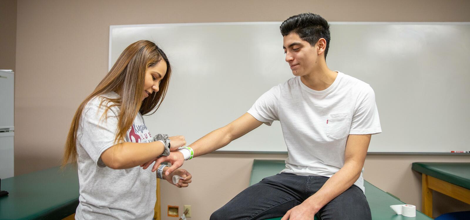 Two students practicing wrapping an injury at the kinesiology building.