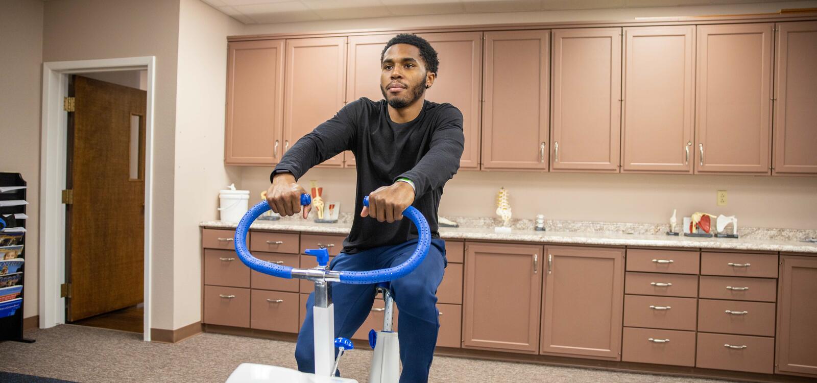 Student using exercise machine in kinesiology building.