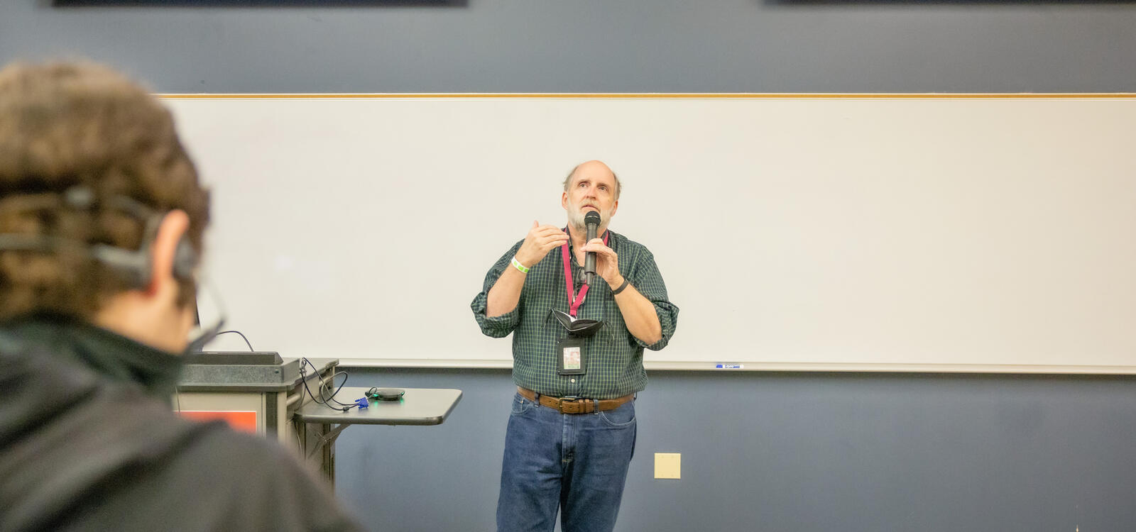 Dr. Jones standing in front of a classroom teaching students as he holds a microphone.