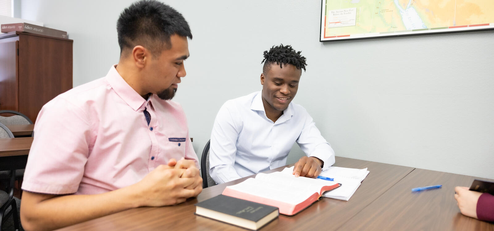 Two male students studying the Bible together and smiling. 