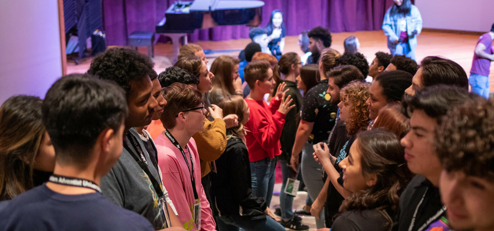 Standing on different steps, two lines of students face each other and converse.