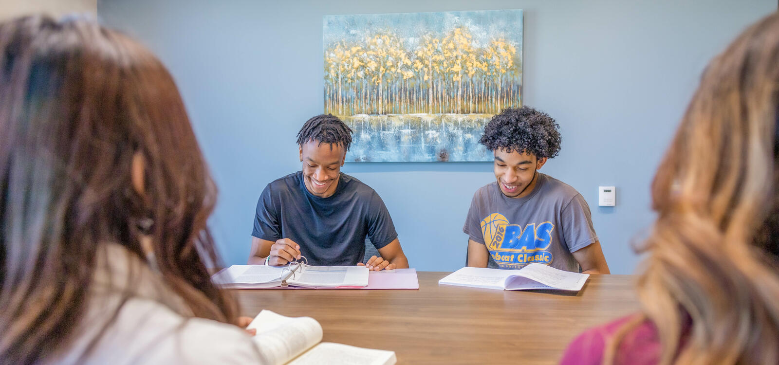 Two male students smiling and reviewing with other students.