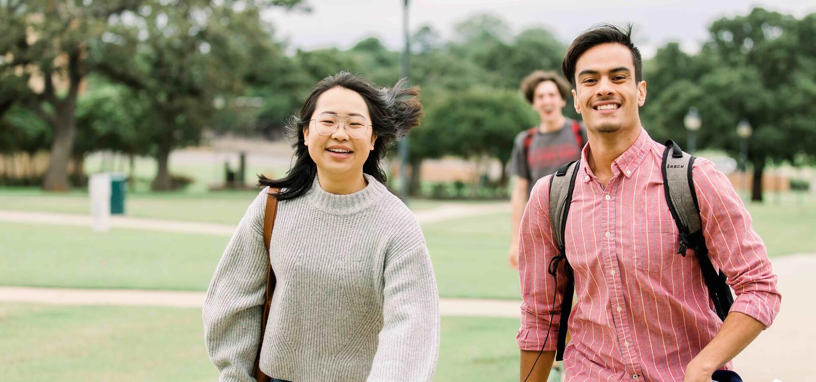 Two students walking across campus together as they talk and smile. 