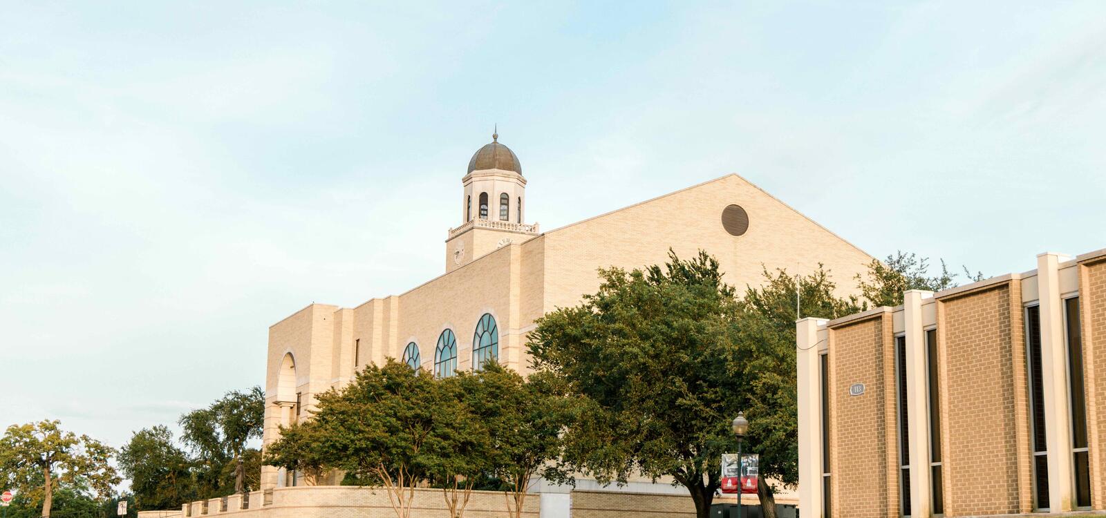 The exterior of the library which is built with light tan bricks and topped with a clocktower