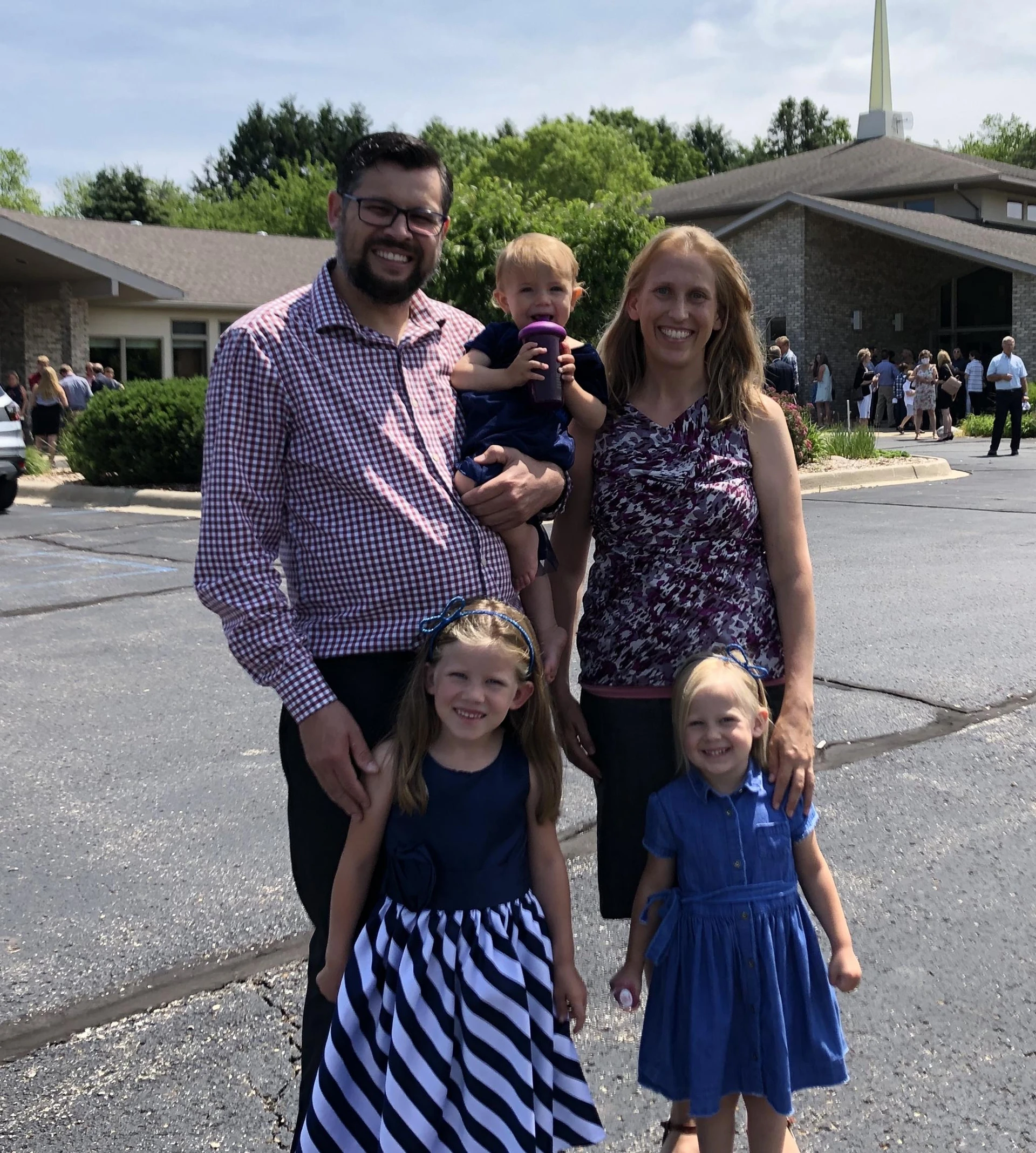 George King holding his baby daughter, standing next to his wife and behind his two other daughters all with big smiles.