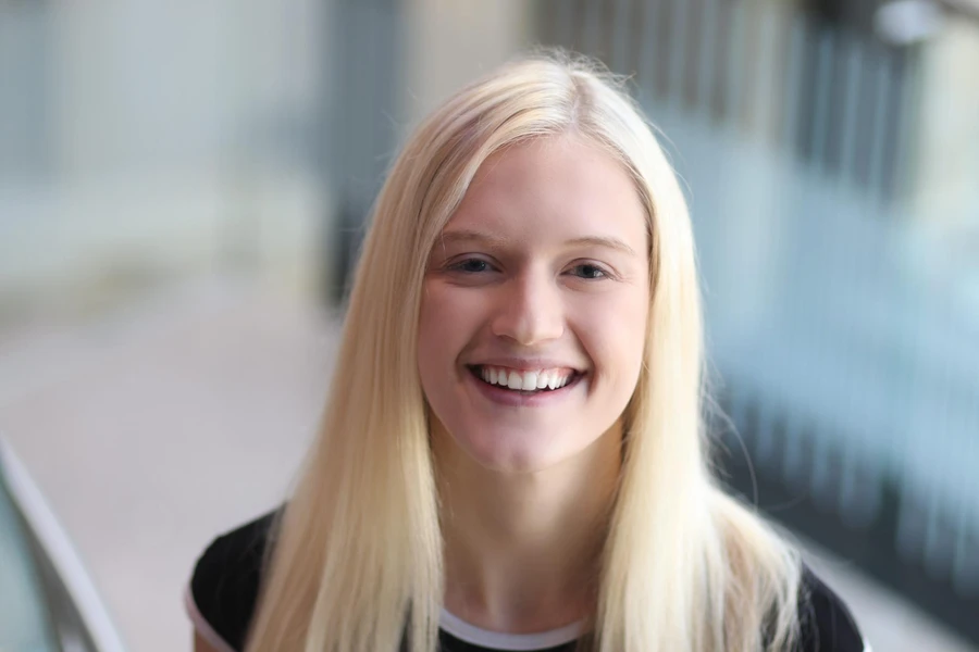 Emily Weaver, a young women with blonde hair, poses looking up at camera and smiling