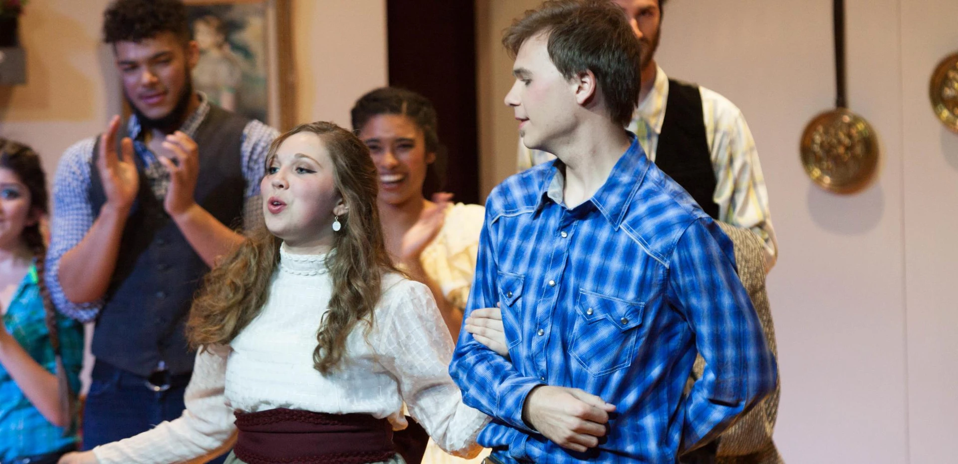 Two students, arms intertwined, stand as their peers can be seen clapping behind them