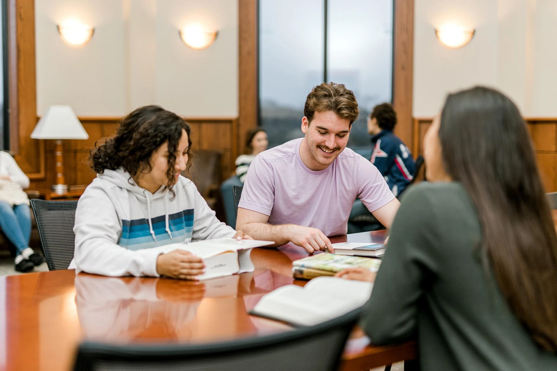 Students sit around a lounge room at tables with their reading books in front of them