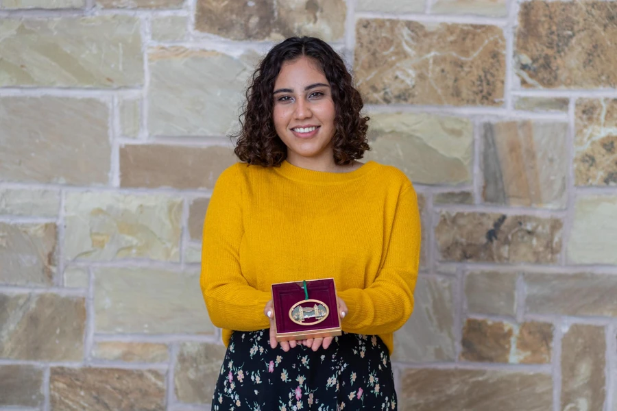 Raquel Villa, dressed in a yellow sweater and flowery black skirt holds the Mizpah ornament.