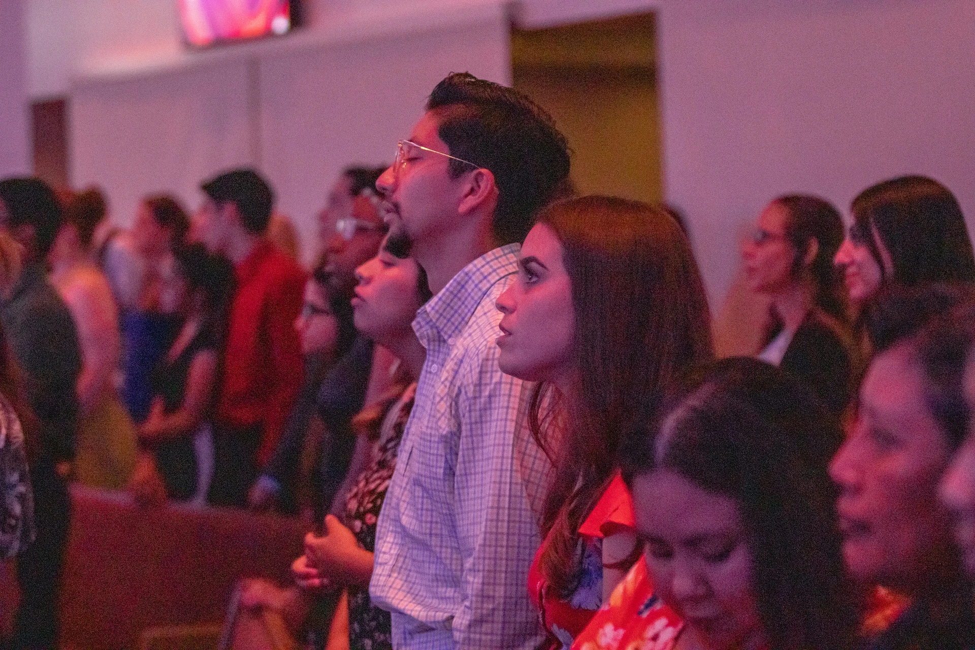 Students, dressed in dresses and button-ups,  gather in the sanctuary stand to sing praise songs